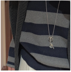 Gros plan du collier avec pendentif lunettes rétro en argent sur un pull rayé