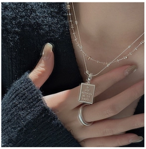 Detail of S925 silver layered necklace set with engraved square pendant on a model