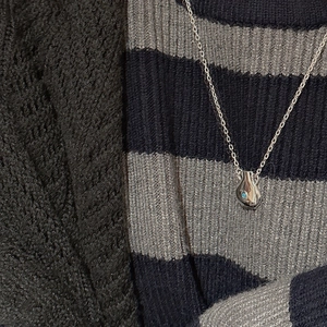 Detail of silver drop pendant necklace with turquoise stone on a knit sweater