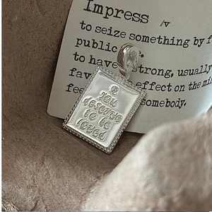 Macro shot of S925 sterling silver square pendant with 'YOU deserve to be loved' engraving