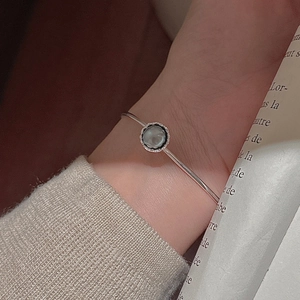 Minimalistischer S925 Silberarmreif mit grauer Perle am Handgelenk einer Frau