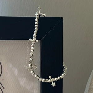 S925 sterling silver beaded bracelet with cross and star charms on a black frame