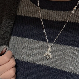 Detail of silver S925 sterling silver necklace with crystal pendant on a striped sweater