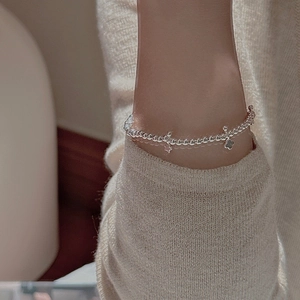 Detail of S925 sterling silver beaded bracelet with star and clover charms on wrist