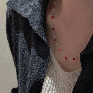 Macro shot of minimalist S925 sterling silver necklace with delicate red faceted beads