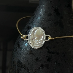 Retro S925 silver crescent moon face cuff bracelet on black textured ceramic base