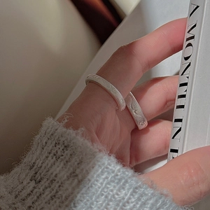 Detail of silver S925 rings featuring brushed texture and hand-engraved wave patterns