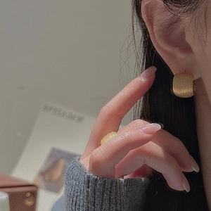 Detailed view of gold earrings and ring featuring vertical brushed metal textures