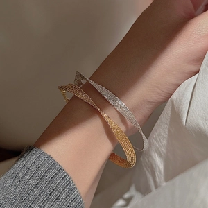 Detail of woven mesh texture on S925 silver and gold minimalist bangle set on wrist