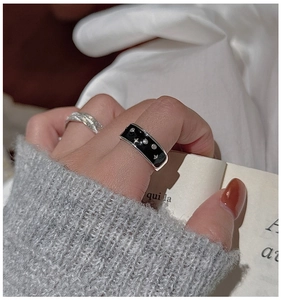 Close-up of stacked S925 sterling silver rings with black enamel star and textured band