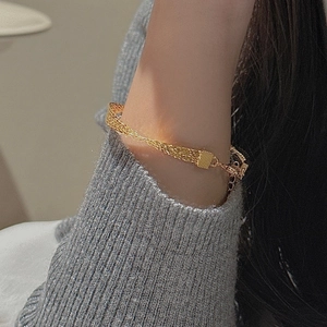Elegant gold multi-strand mesh woven bracelet with extension chain on a model wearing a grey sweater