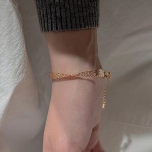 Detail of a thin gold mesh bracelet featuring a flat weave and adjustable extension chain