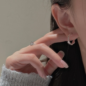 Close-up of minimalist S925 sterling silver hoop earrings and rope knot ring on model