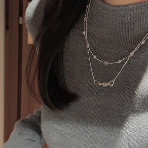 Close-up of double-layer S925 silver necklace with bow pendant and floral bead chain