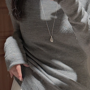 Polished silver teardrop pendant necklace shown on a gray knit sweater texture