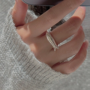Close-up of minimalist S925 sterling silver fish ring worn with a grey knit sweater