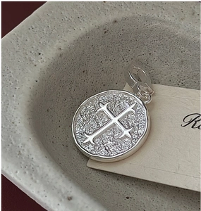 Macro d'un pendentif pièce vintage en argent avec relief croix et texture martelée