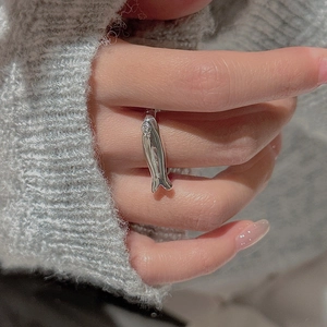 Macro shot of silver fish ring worn over a grey knit sweater showing polished details