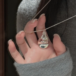 Macro shot of polished S925 sterling silver water drop pendant on a fine O-chain necklace