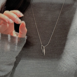 Detail of minimalist S925 silver necklace with sleek teardrop pendant on grey sweater