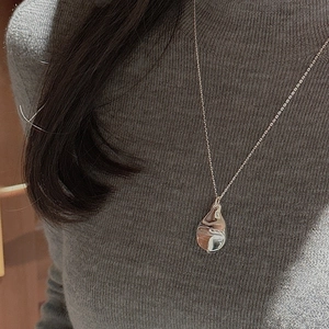 Detail of minimalist 925 silver necklace with teardrop pendant on grey sweater