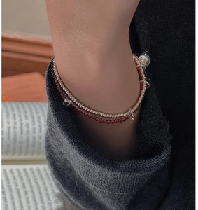 Detail of S925 silver beaded bracelet with red agate and a vintage bell charm