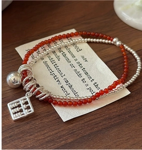 Detailed close-up of a silver abacus and red agate charm on a double-layer vintage bracelet