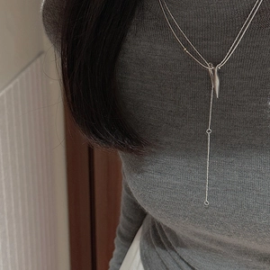Detail view of a double-layered S925 sterling silver Y-shaped necklace on a model's grey sweater