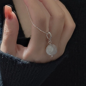 Close-up of S925 sterling silver necklace with translucent round gemstone pendant on hand