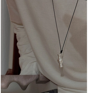 Detail of vintage matte silver vase pendant necklace paired with a black cord on a sweater