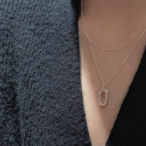 Close-up of a gold geometric oval pendant necklace with a vintage textured finish