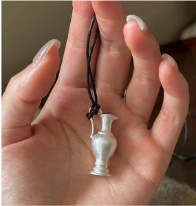 Detailed macro view of a matte S925 silver flower vase pendant held in hand on a black cord
