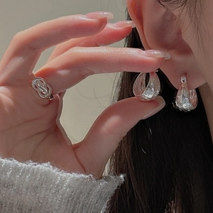 Detail shot of silver earrings with hollow floral pattern and matching rope knot ring