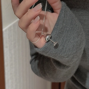 Détail du collier S925 en argent avec pendentif verre à cocktail sur un pull gris