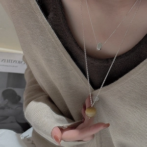 Détail d'un collier double épaisseur en argent minimaliste avec pendentif en pierre œil de tigre