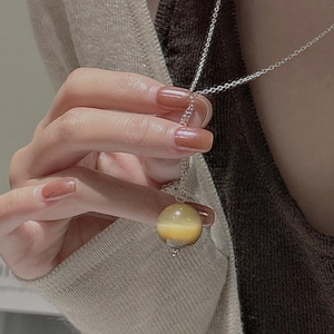 Gros plan d'un collier avec pendentif en pierre œil de tigre tenu à la main