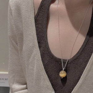 Collier en argent S925 avec pendentif oeil de tigre jaune sur un pull en maille