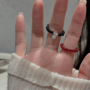 Close-up of S925 silver beaded rings with black agate and red beads on finger