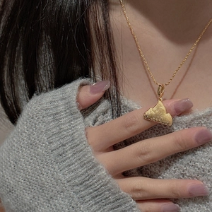 Detail of mountain-shaped gold pendant with matte finish and crystals on a rope chain