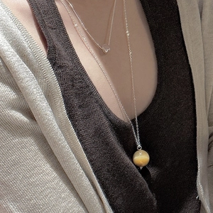 Gros plan sur les colliers superposés en argent S925 avec pendentif rond en oeil de tigre