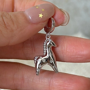 Macro shot of S925 sterling silver pony pendant with zircon stones held by fingers