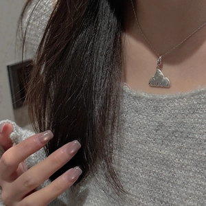 Close-up of minimalist S925 sterling silver mountain pendant on a silver chain necklace