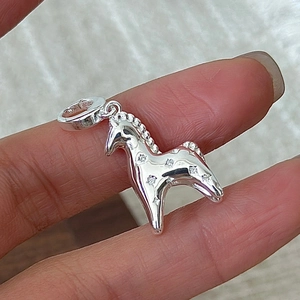 S925 sterling silver pony pendant with star patterns and zircon held between fingers