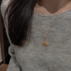 Detailed view of a golden cloud pendant necklace on a delicate chain worn by a model