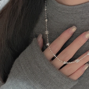 Gros plan du collier en argent S925 avec perles et fleurs ciselées sur un pull en maille