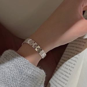 Detail of S925 sterling silver strap bracelet with H-link design on woman wrist
