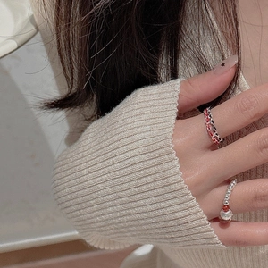 Detail of S925 silver beaded rings with red cord shown on hand in a cozy setting