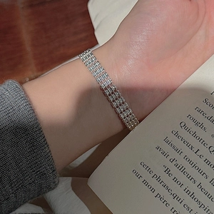 Close-up of a multilayer S925 silver beaded bracelet on a wrist with soft lighting