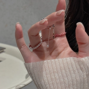 Detail of S925 sterling silver beaded ring and red braided rope ring worn on finger