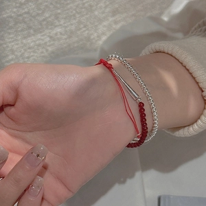 Detail of layered S925 silver bead bracelet and red agate stones on woman's wrist